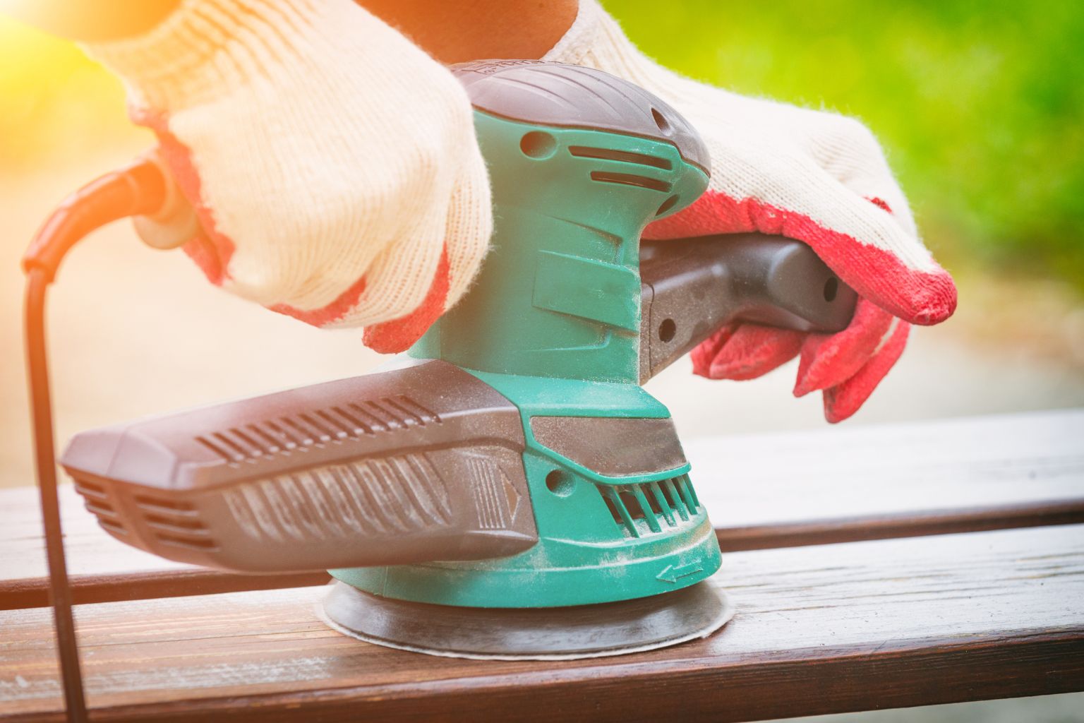 An orbital sander at work on a pieace of wood